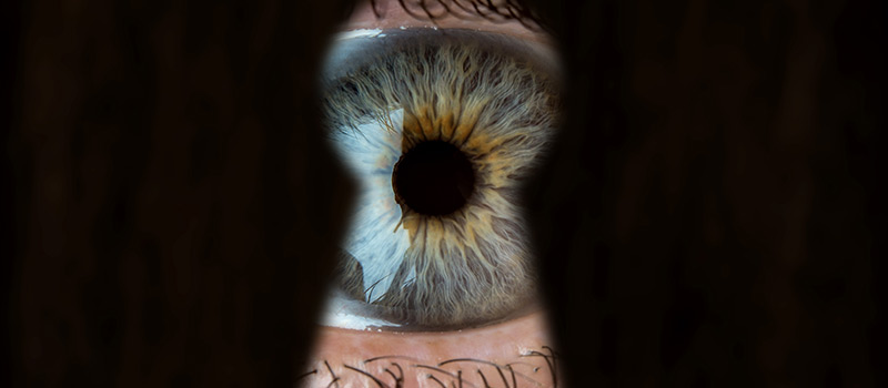 Primer plano del ojo de una persona mirando por una cerradura.