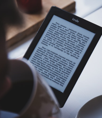 Un hombre leyendo un libro electrónico mientras toma una taza de café