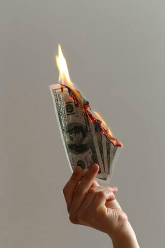 Manu sujetando unos billetes de dólares ardiendo