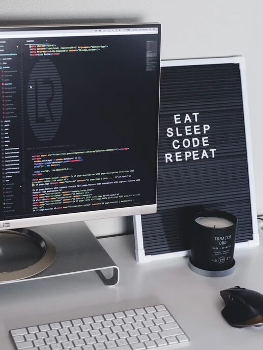Babel AI Avante CRA. Escritorio con un ordenador con código y un cuadro que pone "EAT SLEEP CODE REPEAT"