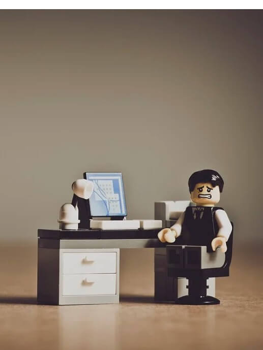 Babel Digital Workplace. A Lego figure of a concerned office worker in front of a computer